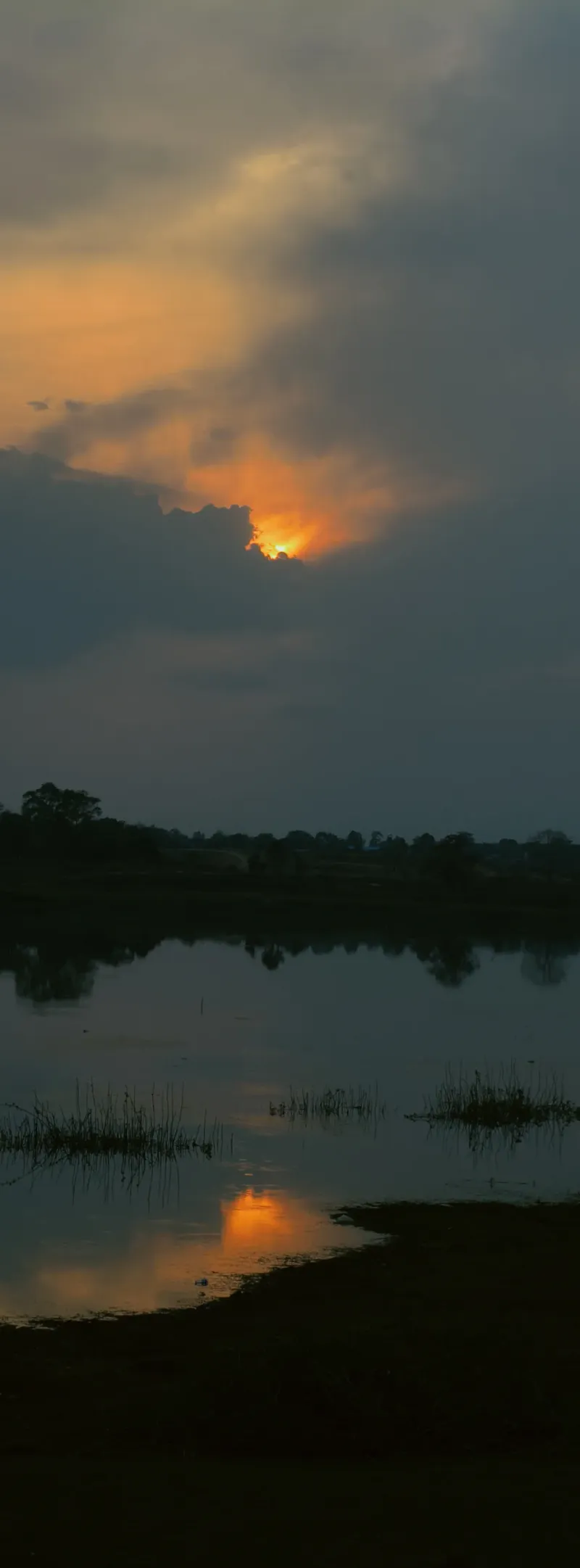 Golden light pierces through clouds, reflecting on serene waters.